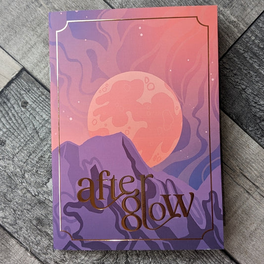 A copy of After Glow laying on a wooden floor