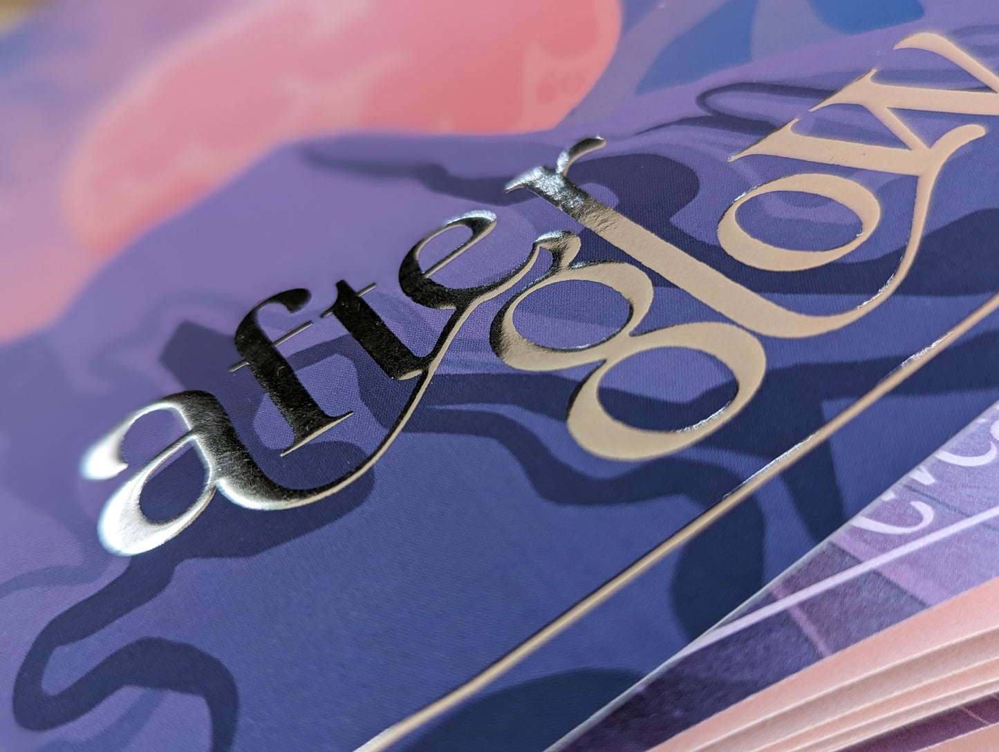 close up image of the gold foiled After Glow logo on the front of the book
